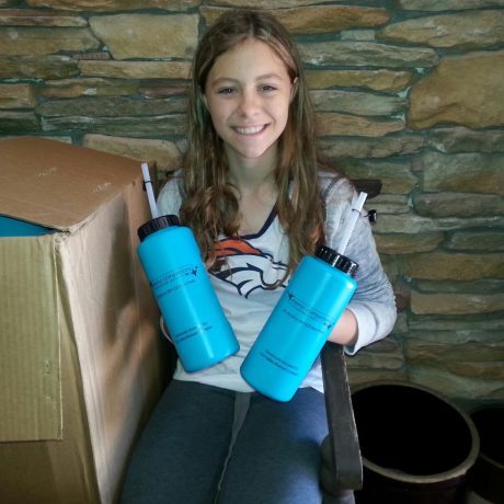 happy little volunteer handing out plastic bottles to cancer patients